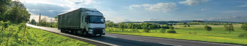 011623 CA Air Regulations_wide White truck driving on the asphalt road in a green rural landscape