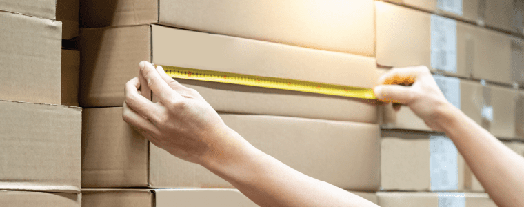 person measuring shipping boxes