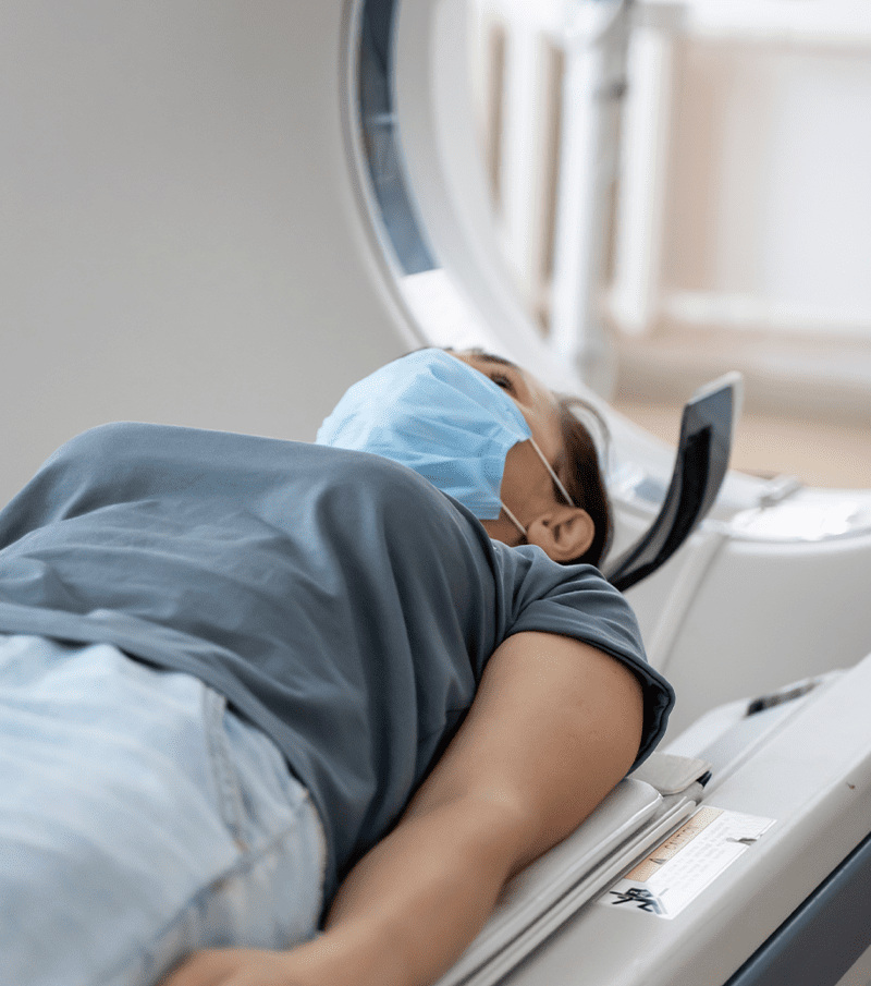 quote medical A woman in a medical mask lies on the tomograph table.